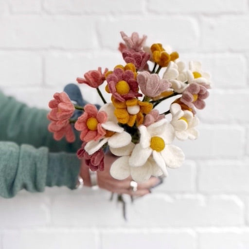Hand holding colourful felt bouquet of flowers.