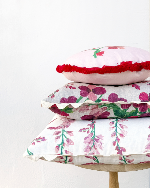Stack of floral Bonnie and Neil cushions on a wooden stool