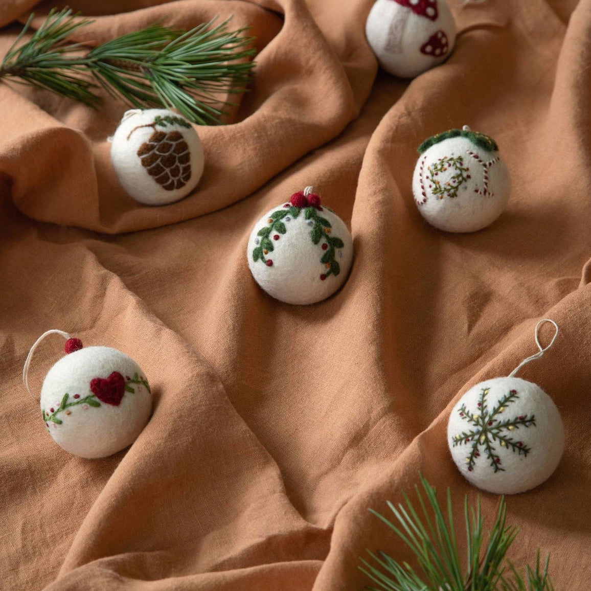 Gry & Sif — Christmas bauble — garland — baubles arranged on fabric with evergreen sprigs
