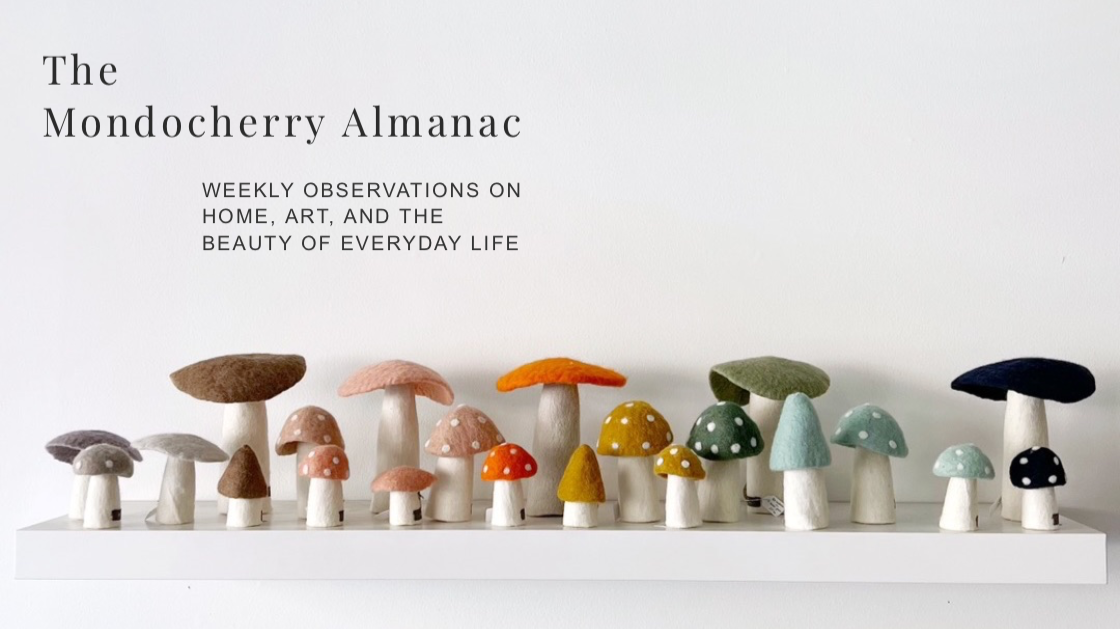 Colourful felt mushrooms on a white shelf.