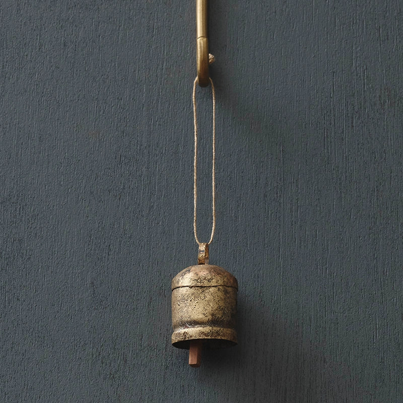 Vintage-style metal bell hanging against a dark gray wall