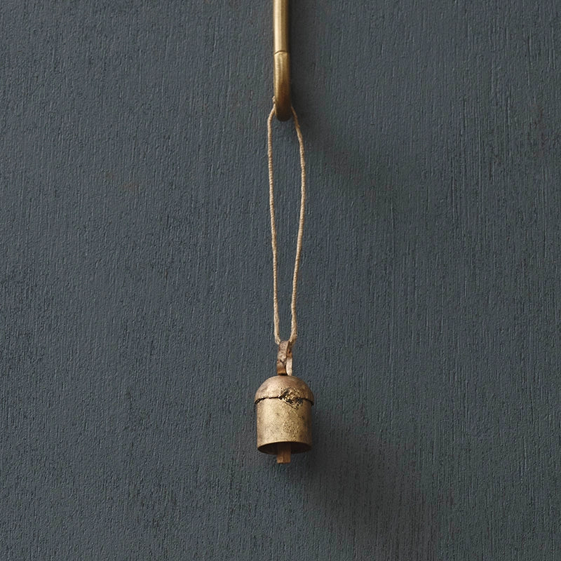 Small brass bell hanging on a dark gray wall