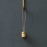 Small brass bell hanging on a dark gray wall