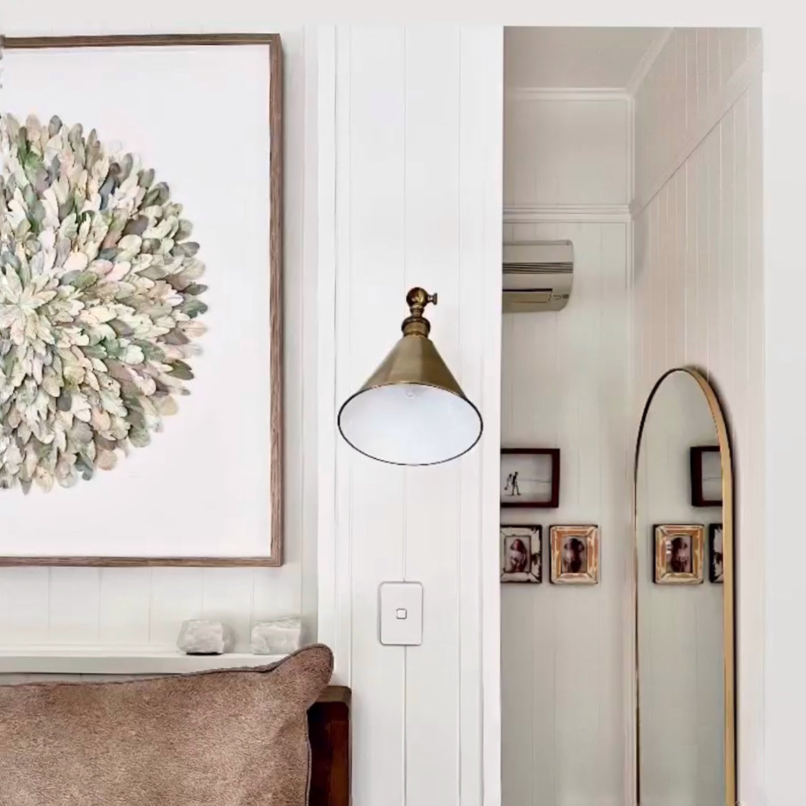 Interior with mondocherry wall art, sconce, and arched mirror.