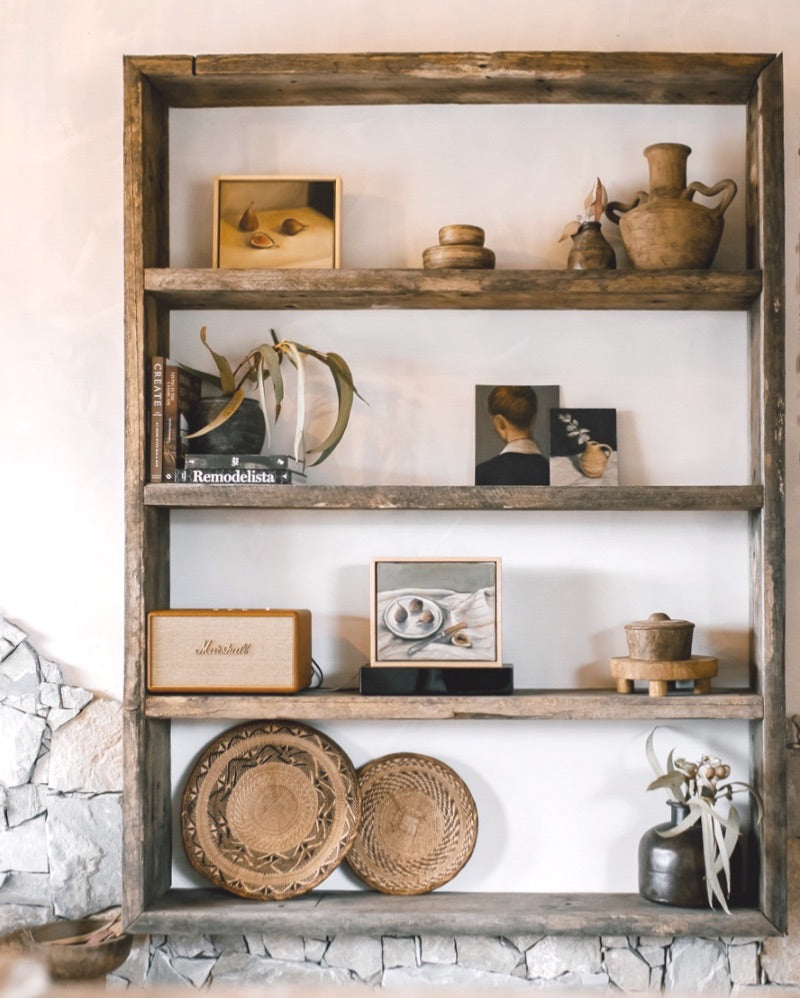 Wooden shelves with art, books, and pottery.
