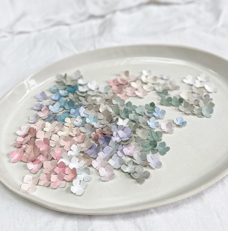 mondocherry colourful paper petals on a white dish.