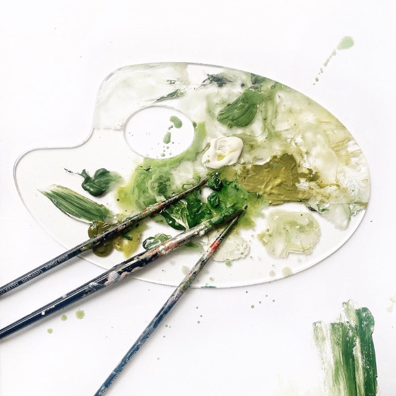 mondocherry paint palette with green hues and brushes.