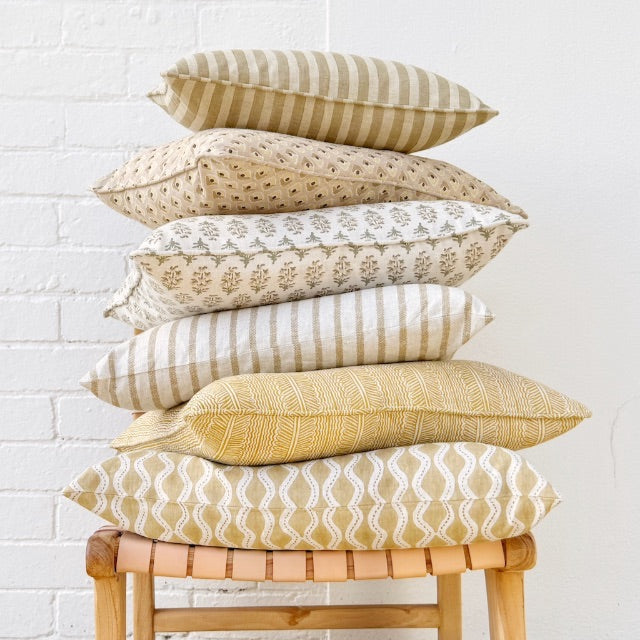 Stack of six Walter G patterned cushions on a chair.