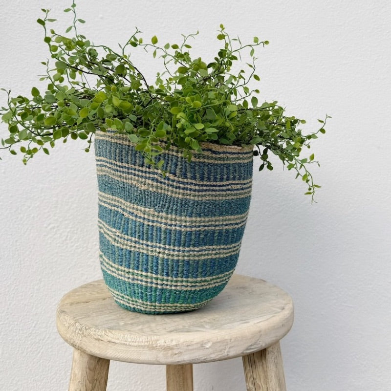 Woven African basket holding a plant on a wooden stool