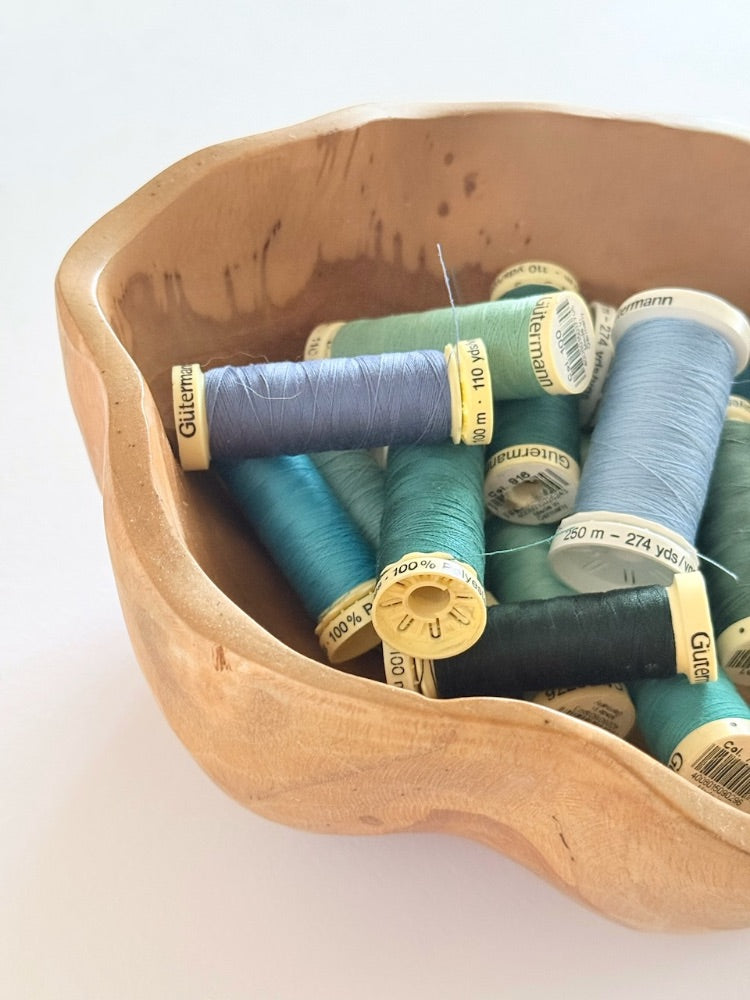 Spools of colourful thread in an antique wooden bowl