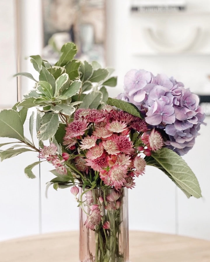 Vase with pink and purple flowers and green foliage
