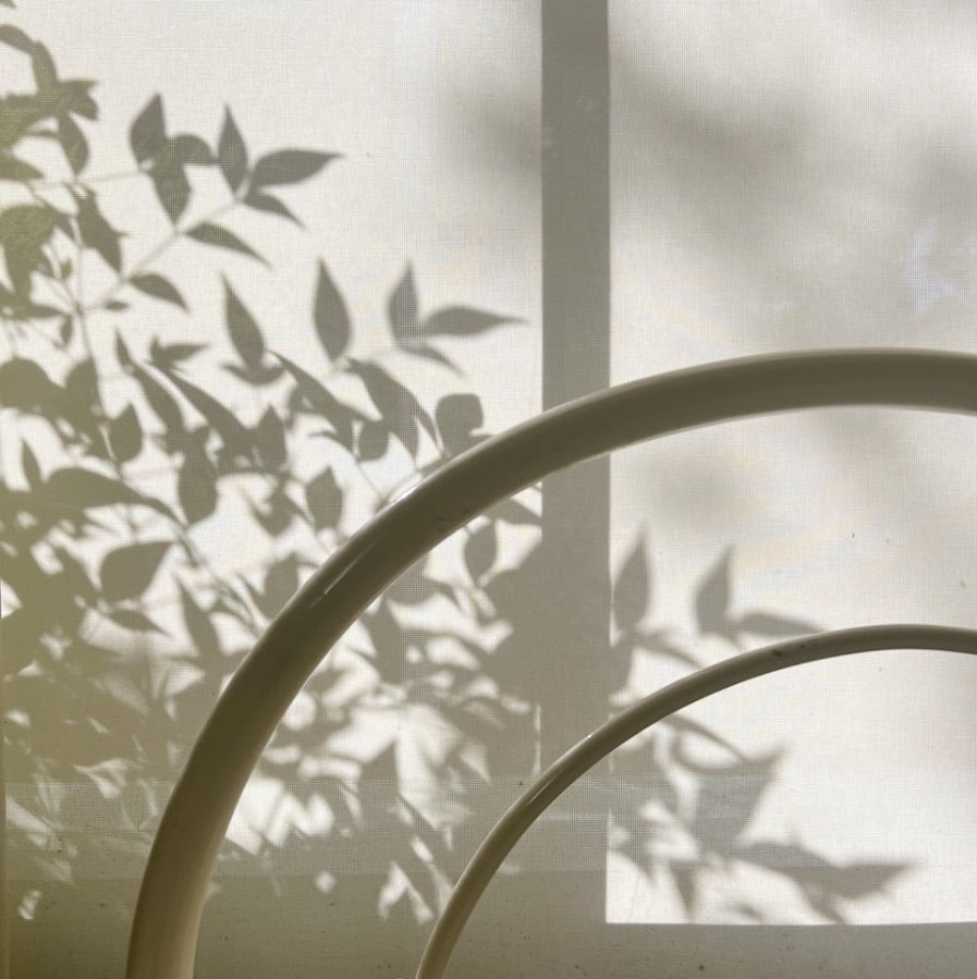 Leaf shadows falling across a white curtain and circular frame