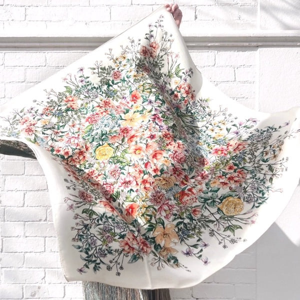Intricate floral scarf held against a white wall