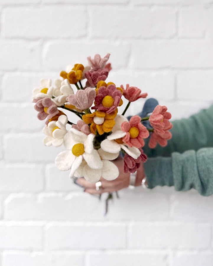 Hands holding colourful Gry and Sif felt flowers