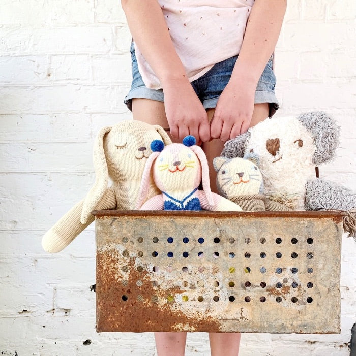 Child holding a basket of knitted BlaBla animal dolls