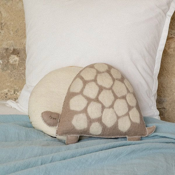 Muskhane turtle-shaped felt cushion on a bed