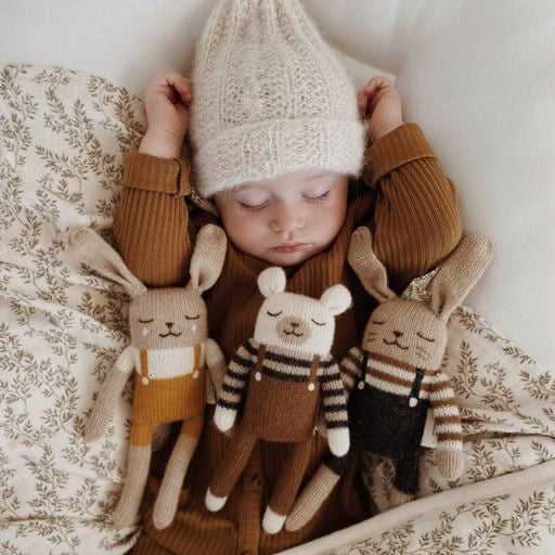 Sleeping baby with knitted Main Sauvage toys.