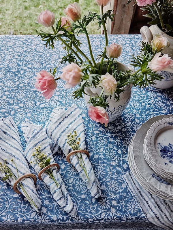 Chamois table setting with flowers, napkins and stacked plates.