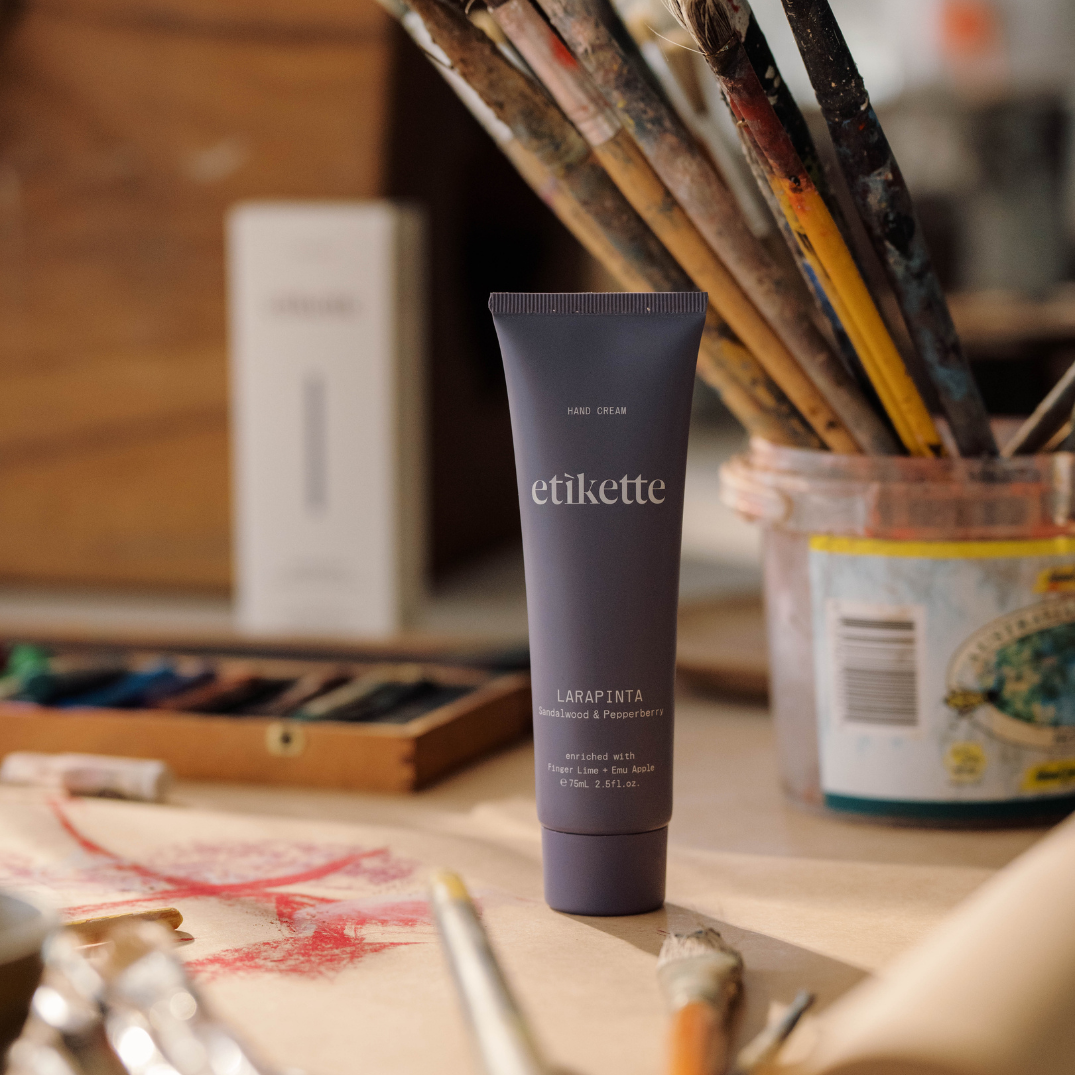 Etikette — hand cream — Larapinta in sandalwood & pepperberry — beside paintbrushes